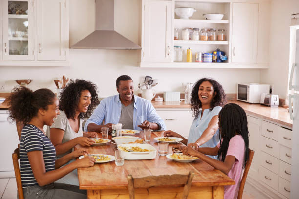 Family With Teenage Children Eating Meal In Kitchen