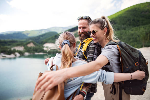 A family of three is on a hiking trip together. Their teenage daughter is embracing a hug from her parents.