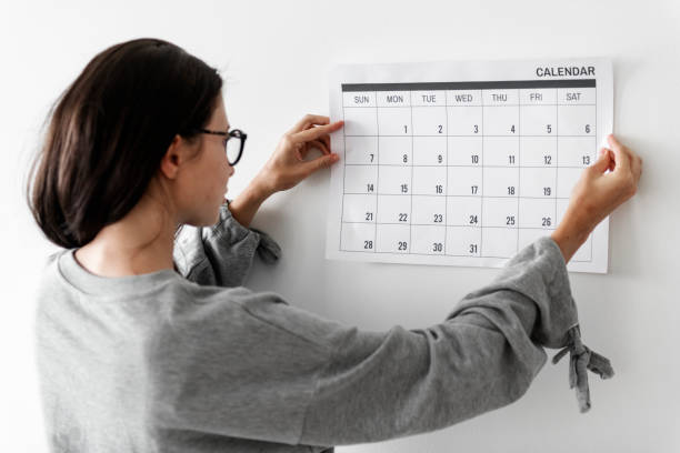 A young woman is looking at her calendar on her wall.