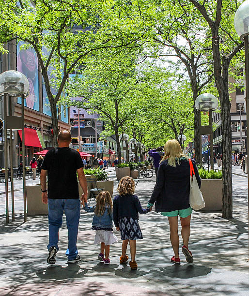 A family of four are on a walk together in the city. They are all holding hands as they walk.