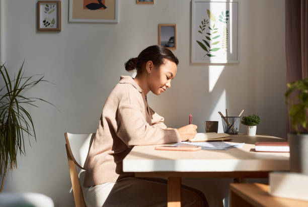 A young African American woman is sitting at her desk, writing.