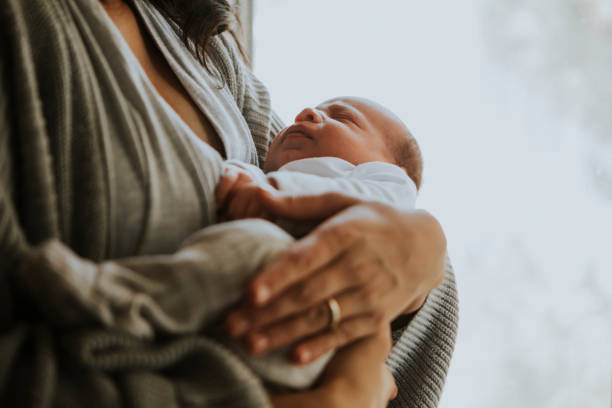 A mother is holding her newborn infant in her arms.