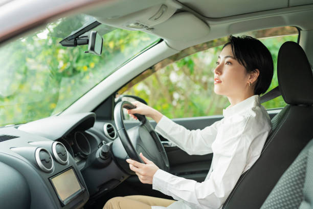 A confident young woman sitting upright in the driver’s seat, holding the steering wheel with both hands and looking ahead calmly.
