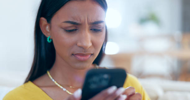 A young biracial woman is looking concerned at her phone.