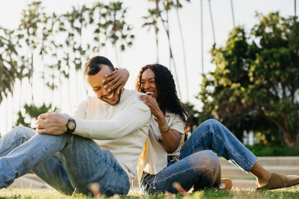Millennial multi ethnic couple enjoying a sunny day at sunset by a public park.