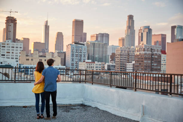 A couple stands on a rooftop at sunset, holding each other while looking out over a city skyline, symbolizing emotional connection, shared goals, and navigating relationship challenges together.
