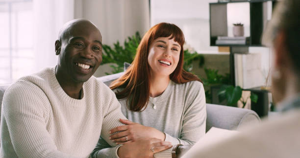 Smiling interracial couple engaging in premarital counseling with a therapist, demonstrating mutual trust and readiness for marriage.