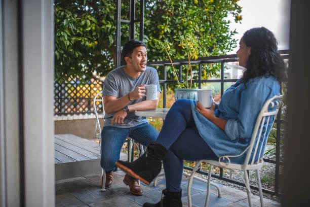 Man offering emotional support to his partner while sitting together on a couch, with the woman looking concerned and the man gently placing his hand on her shoulder in a comforting gesture.