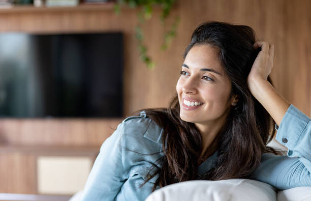 Beautiful Brazilian woman relaxing at home on the couch and smiling - lifestyle concepts
