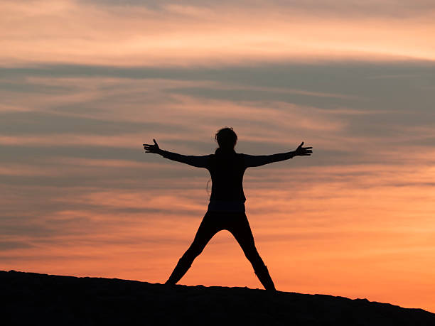 A young woman exercising against the backdrop of the sunset sky on a Los Angeles beach