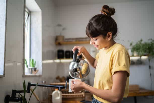 Woman making tea in a kitchen, representing self-regulation and calming down during conflict resolution.