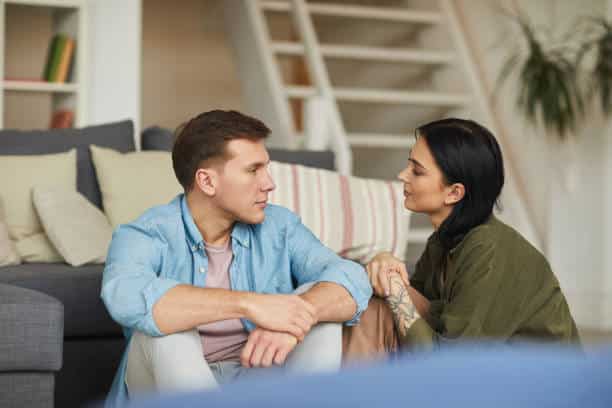Couple sitting face-to-face on the floor having an open and honest discussion to resolve relationship conflict.