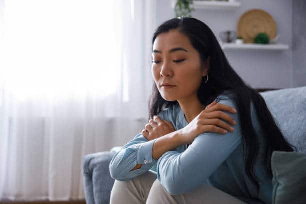 Thoughtful woman resting her head on her hands, appearing preoccupied with intrusive or obsessive thoughts.