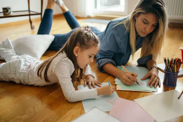 Mother and young child lying on the floor drawing together, supporting creativity and emotional expression.