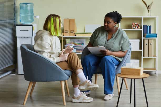 Child speaking with a therapist during a counseling session, discussing emotions and behaviors in a supportive setting.