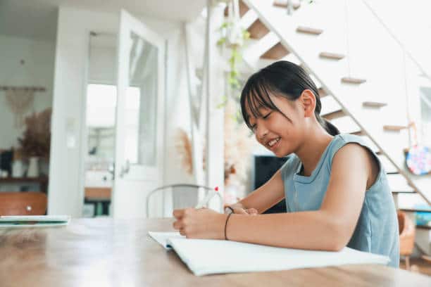 Student sitting at a table and writing in a notebook, demonstrating a structured and productive study routine.